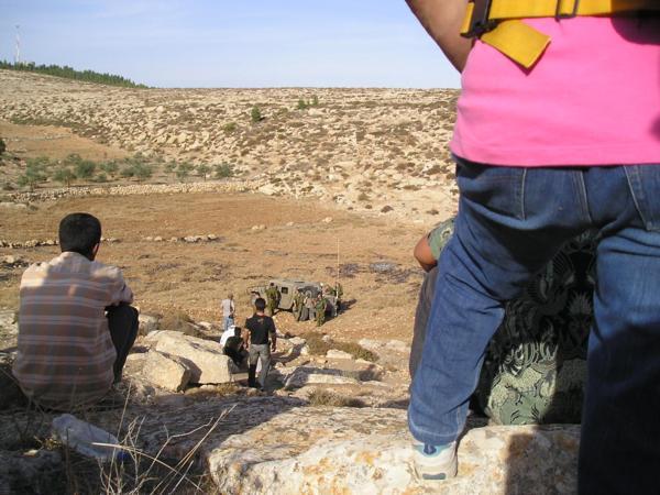 Připadám si nemístně. Celá situace je absurdní - zhruba čtyřicet lidí sedí s rukama v klíně ve čtyřicetistupňovém vedru - farmáři, vojáci, policie, osadníci a dvě skupiny dobrovolníků. Předmětem sporu je pole s nekvalitní kamenitou půdou zhruba o velikosti Staroměstského náměstí. Vytahuji z batohu Chumaš a začínám se učit na Shayiovu hodinu na druhý den