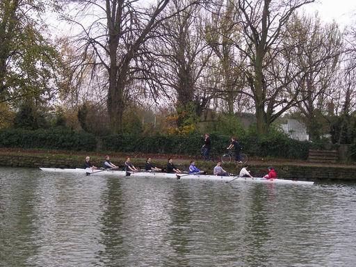Trénink. Na břehu jede trenér na kole a udílí pokyny/Outing. The guy on the bike on the river bank is the coach